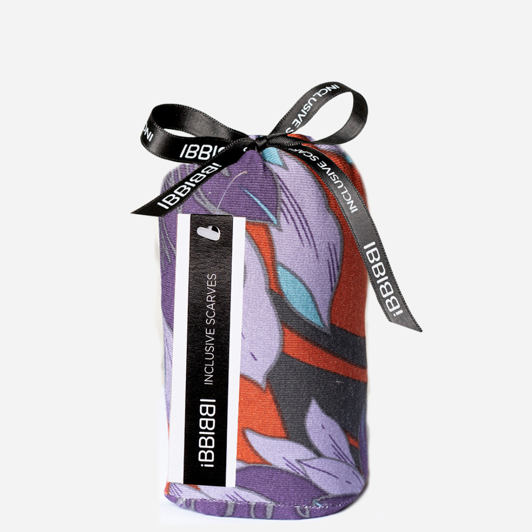 Pañuelo oncológico Kyoto de iBBIBBI plegado en su packaging, con diseño colorido y lazo negro elegante.